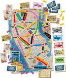 Ticket to Ride: New York board game featuring a colorful map of Manhattan with routes, playing pieces, and destination cards. The map highlights iconic locations such as Times Square, Central Park, and the Empire State Building, along with game components like trains and ticket cards in vibrant colors.