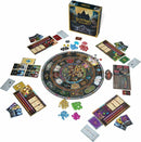 An image of the board game Weirdwood Manor by GREYRIDGE GAMES. The game includes a circular game board with various colorful tokens, cards, and player boards scattered around it. The box is prominently displayed at the back, featuring the game's title and a spooky illustration of a manor.