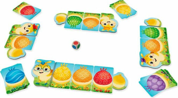 The Rainbow Caterpillar game by HABA features colorful puzzle pieces laid out on a bright, grassy area. Players can see charming animal characters and colorful caterpillar sections, alongside a multicolored dice, inviting a fun-filled gameplay experience for children.