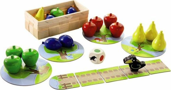 My First Orchard game by HABA USA features colorful fruit pieces including red apples, green apples, yellow pears, and blue fruits. It comes with a wooden basket, tree-themed game boards, a dice with animal symbols, and a playful crow figure. This engaging game is designed for young children, encouraging teamwork and color recognition while having fun in an orchard-themed setting.