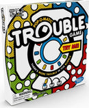 The Trouble game by Hasbro features a colorful, pop-o-matic design on the box with the game title prominently displayed. It indicates playing age 5+, suitable for 2-4 players. The box has a 'Try Me!' tag and a warning label about small parts. The vibrant colors and iconic bubble feature promise fun and excitement in gameplay.