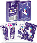 Bicycle Unicorn playing cards featuring a vibrant purple deck with a majestic unicorn illustration on the back. The front displays the Queen of Clubs, King of Diamonds, and Ace of Spades, highlighting the whimsical design and air cushion finish that ensures smooth gameplay.