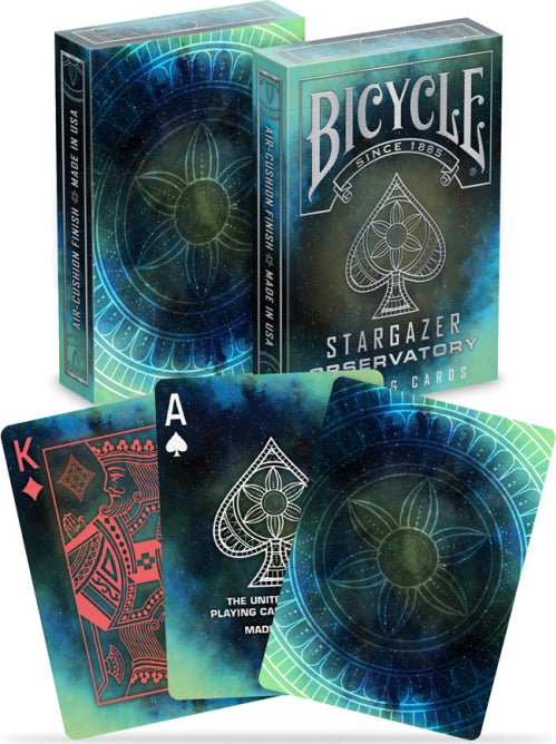 Bicycle Stargazer Observatory playing cards set, featuring a cosmic design with a starry background. The card backs display a unique floral pattern with vibrant blues and greens, while the top cards show a King of Diamonds and an Ace of Spades, all produced by the US Playing Card Company.