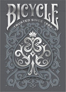 A beautifully designed Bicycle Cinder deck of playing cards, featuring an ornate gray background with a decorative spade symbol embellished with intricate designs. The top reads 'Bicycle' and 'Trusted Since 1885', showcasing the brand's classic and premium quality.