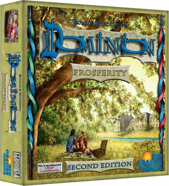The Dominion: Prosperity board game by Rio Grande Games features a beautifully illustrated box cover. The artwork depicts a serene outdoor scene with two characters seated under a large tree, enjoying the landscape that includes a distant building. The title 'Dominion' is prominently displayed in stylized blue letters across the top, with 'Prosperity' below it. The box also includes a note indicating this is an expansion, not a complete game.