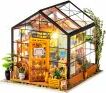 Cathy's Flower House Model Kit by Robotime, featuring a beautifully detailed miniature greenhouse with plants, a welcoming door, and an inviting interior setup, perfect for DIY enthusiasts and crafters.