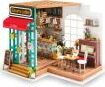 Simon's Coffee Model Kit by Robotime showcases a detailed coffee shop interior with a bright red awning, tables, chairs, and decorative items like books and plants.