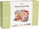 The Honey Ice Cream Shop Model Kit by Robotime features a beautifully detailed miniature ice cream shop with vibrant colors and intricate design elements. This DIY kit includes various components to assemble a charming ice cream parlor scene, perfect for hobbyists and craft enthusiasts. The packaging showcases the completed model, offering a glimpse of the delightful storefront and cozy interior, inviting creativity and imagination.