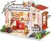 A detailed model kit of a Honey Ice Cream Shop featuring intricate design elements, including a shopfront with a sign, outdoor seating, and miniature decorations. The kit showcases vibrant colors and realistic accessories, making it ideal for DIY enthusiasts and hobbyists.