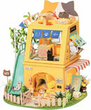A colorful DIY miniature cat house by Robotime, featuring a whimsical two-story design with a slide, trees, and various cat figurines. The house is adorned with banners, a play area, and flower decorations, inviting creativity and playfulness for cat lovers.