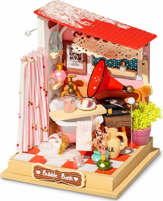 A detailed Bubble Bath Bathroom Model Kit by Robotime featuring a miniature bathroom scene. The kit includes elements like a pink bathtub, shower curtains, decorative plants, and a vintage gramophone. Vibrantly designed with various accessories that create a cozy and nostalgic atmosphere, perfect for DIY enthusiasts.