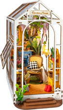 A detailed DIY miniature model of a Garden House by Robotime, featuring a cozy interior with a chair, potted plants, decorative lighting, and floral accents. The structure has a charming design that showcases a vibrant, inviting atmosphere ideal for hobbyists and craft lovers.