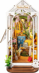 The Garden House DIY Book Nook is a charming miniature model featuring a cozy indoor garden scene. It includes details like vibrant flowers, a comfortable chair, colorful cabinets, and decorative elements. The design is intricate, showcasing a warm atmosphere with hanging plants and a stylish aesthetic, ideal for book lovers and DIY enthusiasts.