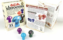 Stat Trackers: 'shrooms game by TopDog Games featuring three collectible mushroom figurines in various colors. The box shows the title and contains an informative card with a 'shroom decoder explaining the magical effects associated with each type of mushroom. The mushrooms are displayed in a clear arrangement, highlighting their unique colors and designs.