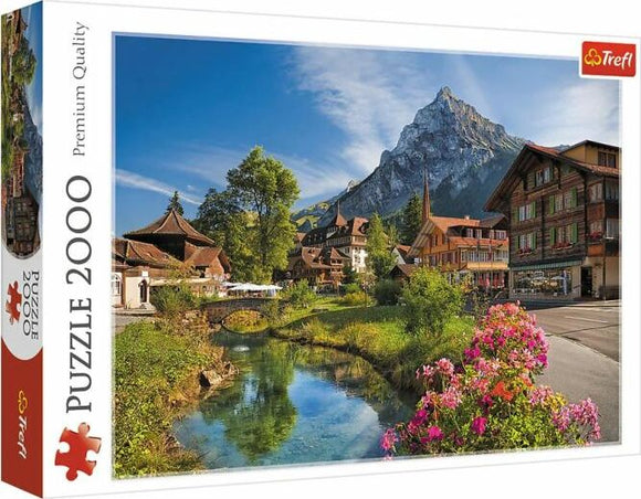 Trefl jigsaw puzzle titled 'Alps in the Summer', featuring a scenic view of picturesque Swiss houses alongside a serene river, surrounded by lush greenery and majestic mountains under a bright blue sky. The puzzle consists of 2000 pieces, ideal for nature lovers and puzzle enthusiasts.