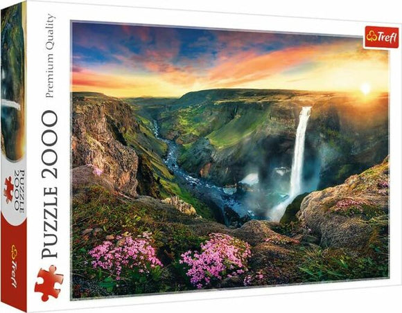 Trefl jigsaw puzzle featuring the stunning Háifoss Waterfall in Iceland. This 2000-piece puzzle showcases breathtaking scenery of the waterfall surrounded by lush hills, rocky cliffs, and colorful wildflowers under a vibrant sky at sunset.
