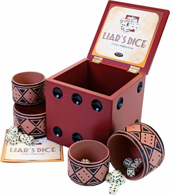 Liar's Dice game set by University Games, featuring a decorative red box with black dots, a stack of two tribal-patterned cups, and dice scattered around. The game is laid out with the instruction booklet visible, showing the classic bluffing game elements.