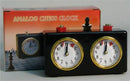 Wind-Up Analog Chess Clock from WorldWise Imports, featuring two round clock faces with gold rims and easy-to-read white dials. The clock is designed for timing chess games, with red buttons for switching between players. The packaging showcases a chess-themed design, enhancing the game experience for chess enthusiasts.