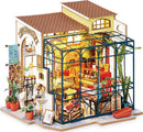 A detailed DIY model kit of Emily's Flower Shop by Robotime, featuring a beautifully designed flower shop with a greenhouse, vibrant flower pots, and charming decor elements. The model showcases intricate interior furnishings, including shelves filled with plants, a cozy seating area, and a bright, inviting atmosphere. Perfect for crafting enthusiasts who enjoy building miniature scenes.