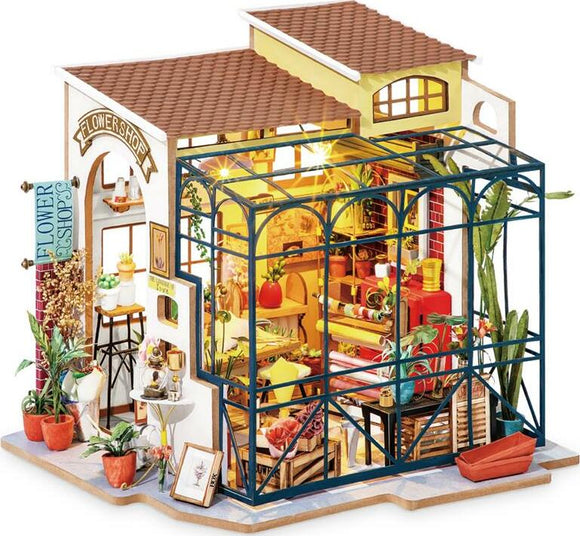 A detailed DIY model kit of Emily's Flower Shop by Robotime, featuring a beautifully designed flower shop with a greenhouse, vibrant flower pots, and charming decor elements. The model showcases intricate interior furnishings, including shelves filled with plants, a cozy seating area, and a bright, inviting atmosphere. Perfect for crafting enthusiasts who enjoy building miniature scenes.
