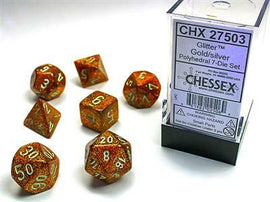 A set of seven glittery gold and silver polyhedral dice by Chessex, displayed with the clear packaging. The dice feature various shapes, including d20, d12, and d10, each covered in shimmering glitter, showcasing vibrant colors and engraved numbers for easy reading.