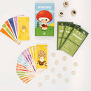 Kinoko game by Helvetiq features a colorful box with a cute character holding a mushroom, surrounded by vibrant cards and game pieces. The contents include skillfully illustrated cards in various colors, dice, and instruction booklets in multiple languages, all designed for an engaging and fun gameplay experience.