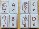 A set of Sign Language Alphabet Tiles, featuring raised letters A, B, C, and D alongside corresponding hand signs. Each tile is rectangular with a white textured background and brown illustrations of the letters and signs, designed for educational play.