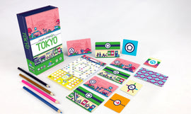 Next Station Tokyo game by Blue Orange U.S.A. displayed with various colorful cards and a game board. The vibrant packaging features Tokyo scenery, including iconic buildings and characters. Accompanied by colored pencils, ready for an engaging game night.
