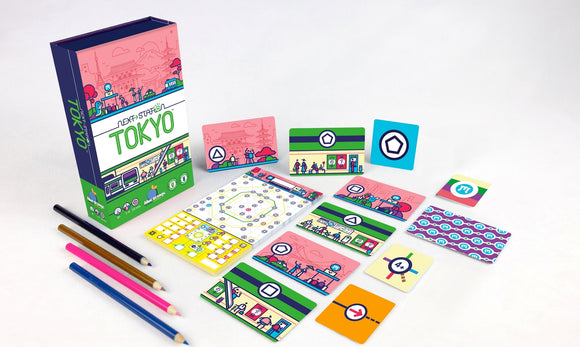 Next Station Tokyo game by Blue Orange U.S.A. displayed with various colorful cards and a game board. The vibrant packaging features Tokyo scenery, including iconic buildings and characters. Accompanied by colored pencils, ready for an engaging game night.