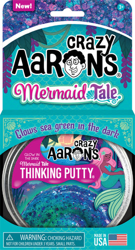 A vibrant 4-inch container of Crazy Aaron's Thinking Putty in the Mermaid Tale variety. The putty features a shimmering sea green and blue color, embedded with glitter, and glows in the dark. The packaging showcases playful mermaid graphics and includes a warning for small parts, indicating it's not suitable for children under three. Made in the USA.