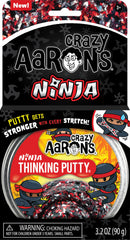 A pack of Crazy Aaron's Thinking Putty Ninja 4" in a clear container. The putty features a colorful black, red, and silver design. The packaging showcases a playful ninja character and includes a warning about choking hazards for children under 3 years, emphasizing its fun and stretchable qualities.