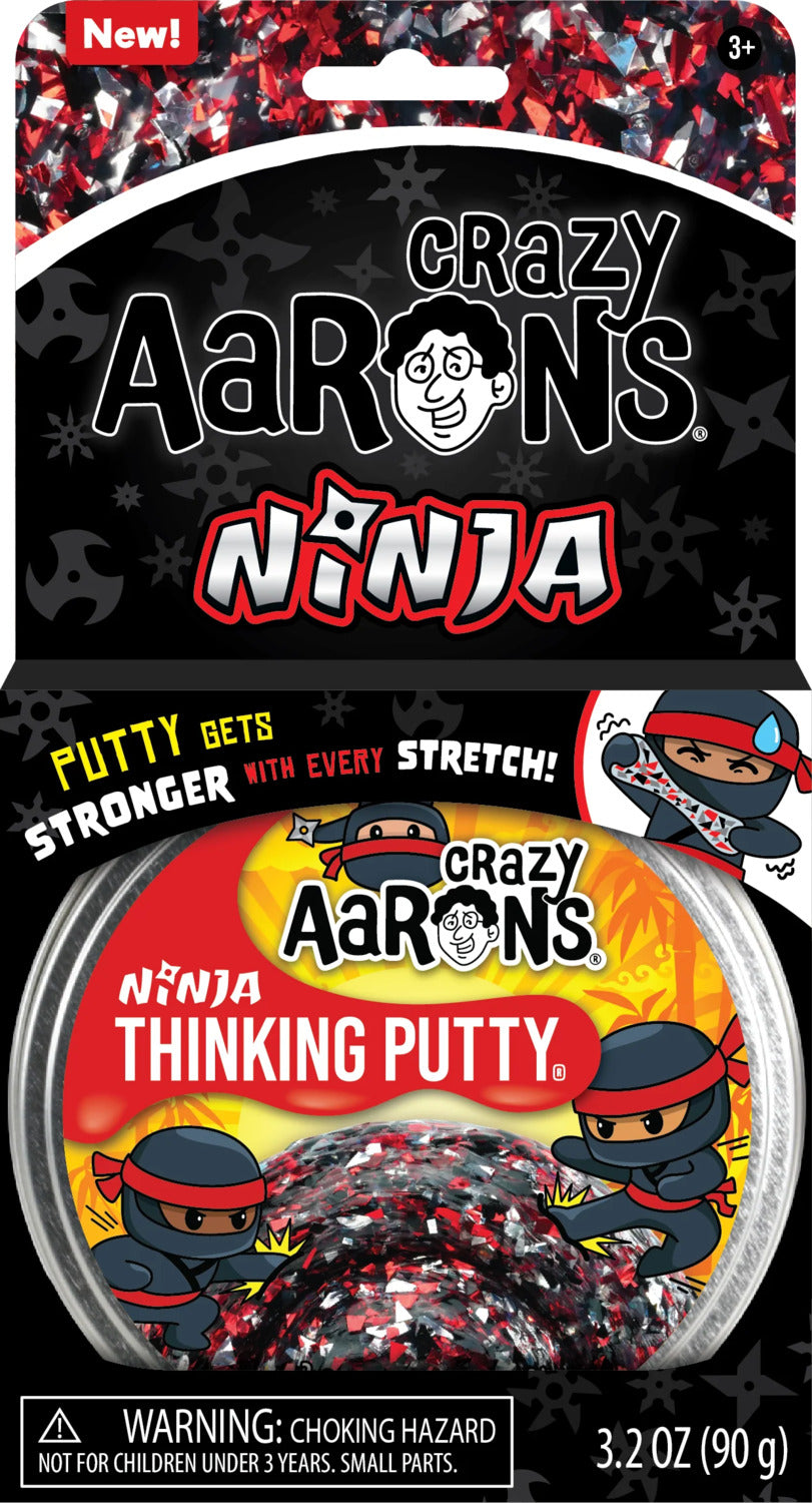 A pack of Crazy Aaron's Thinking Putty Ninja 4" in a clear container. The putty features a colorful black, red, and silver design. The packaging showcases a playful ninja character and includes a warning about choking hazards for children under 3 years, emphasizing its fun and stretchable qualities.