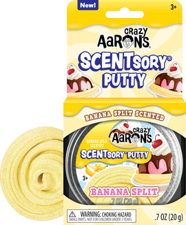 A colorful packaging of Crazy Aaron's Scentsory Putty in Banana Split scent. The package features an illustration of a dessert with a cherry on top, accompanied by a circular swirl of the yellow putty. The label indicates it's scented, suitable for ages 3 and up, and weighs 0.7 oz (20 g).