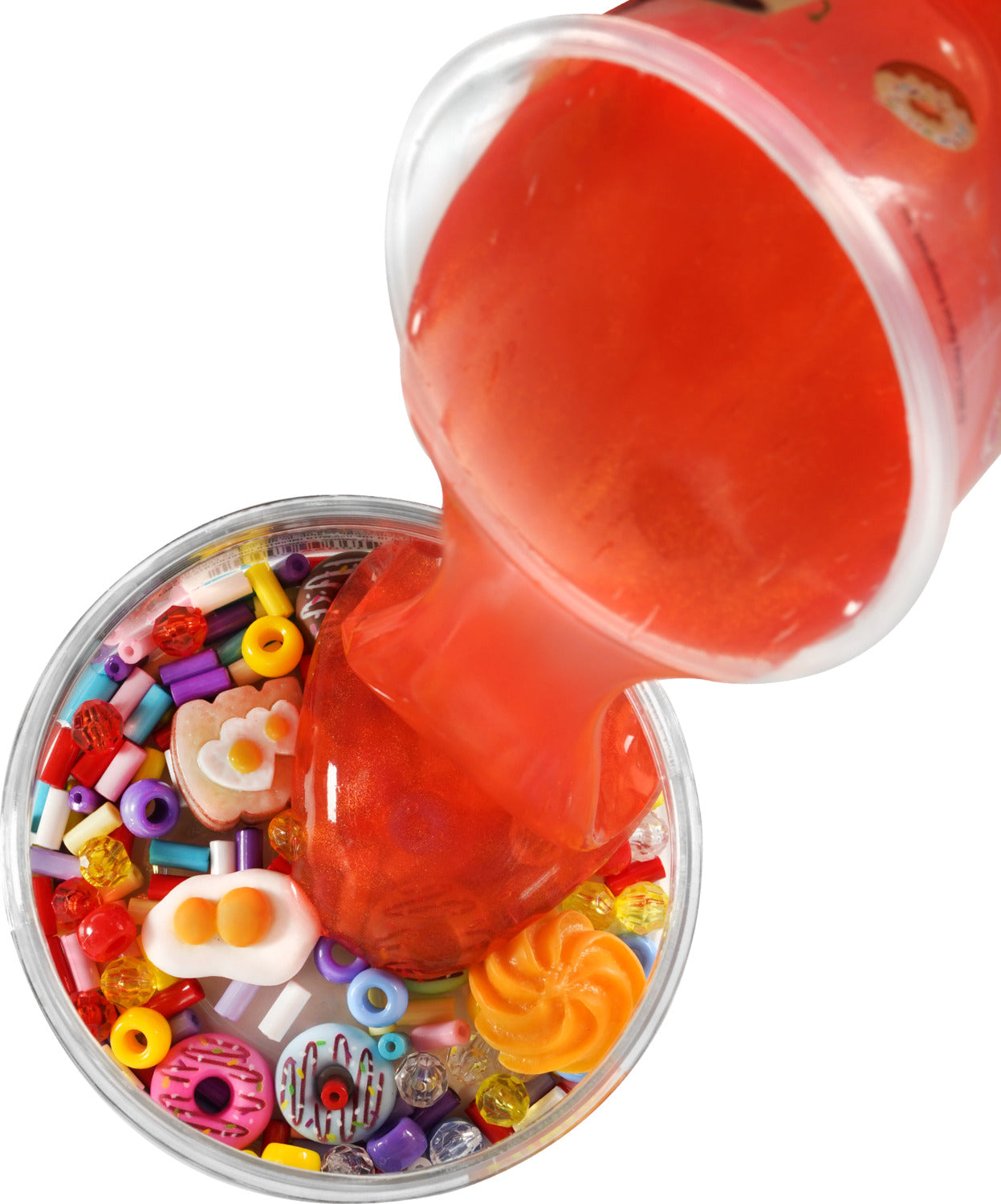 A close-up image of Sunny Side Up Slime Charmers by Crazy Aaron. The image shows a vibrant orange slime being poured into a clear container filled with colorful beads, sprinkles, and donut-shaped charms, providing a sensory-rich visual experience.