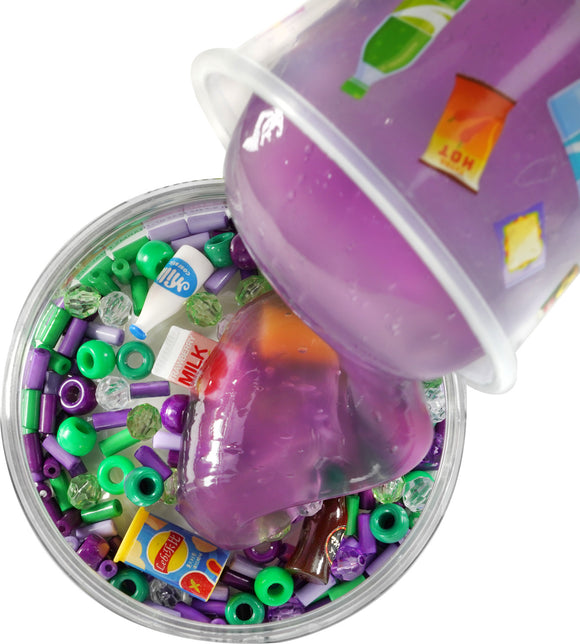 A close-up shot of Mini Mini Mart Slime Charmers from Crazy Aaron's Puttyworld. The image captures colorful beads and mini food and drink items embedded in a purple slime. The slime is being poured from a cup, showcasing a mix of vibrant textures and playful elements, perfect for sensory play.
