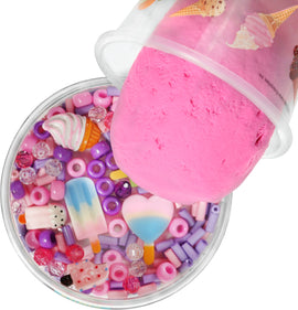 A clear container filled with colorful beads and charms, including pink and purple accessories, topped with a large pink slime that resembles ice cream. The assorted pieces feature miniature ice cream cones, popsicles, and heart shapes, perfect for imaginative play.