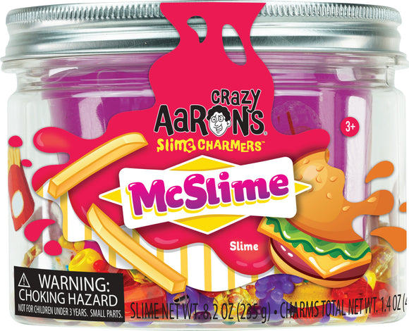 A jar of Crazy Aaron's McSlime Slime Charmers, featuring vibrant purple slime mixed with colorful charm pieces including food and fruit shapes. The jar is transparent with a silver lid, labeled with cheerful graphics and a warning about choking hazards for children under three years. The product is suitable for ages 3 and up.