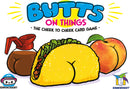 Butts on Things card game by Gamewright featuring playful illustrations of a peach, a taco, and a coffee pot each with cartoonish butt shapes. The title 'Butts on Things - The Cheek to Cheek Card Game' is prominently displayed.