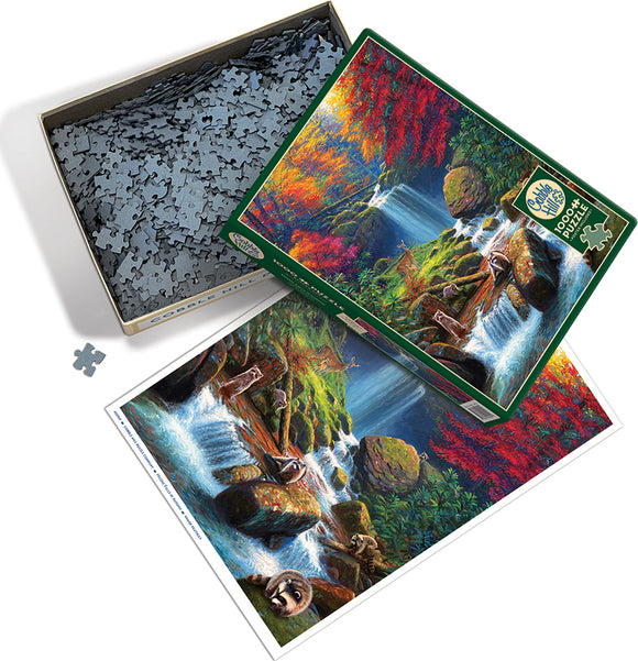 Cobble Hill jigsaw puzzle titled 'Mystic Falls in Autumn'. The box contains numerous grey puzzle pieces, and the image on the box showcases a vibrant landscape with a waterfall surrounded by colorful autumn foliage, rocks, and playful otters.