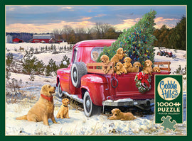 A vibrant jigsaw puzzle titled 'Family Outing' by Cobble Hill. Illustration features a red vintage truck carrying a decorated Christmas tree and playful golden retriever puppies in a snowy landscape with farm buildings in the background.