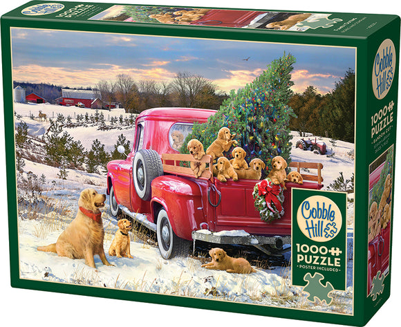 Cobble Hill jigsaw puzzle titled 'Family Outing', featuring a charming winter scene with a vintage red truck carrying a Christmas tree, surrounded by playful golden retriever puppies and a snowy landscape. Includes a poster.