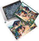 The 'Fountain on the Square' jigsaw puzzle by Cobble Hill features a vibrant illustration of a charming town square with quaint buildings, colorful flowers, and a lovely fountain. The image displays the assembled artwork alongside the puzzle pieces in the box, showcasing the puzzle's intricate design. The box is open, revealing many jigsaw pieces waiting to be assembled.