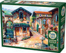 Cobble Hill jigsaw puzzle titled 'Fountain on the Square', featuring a charming village scene with cobblestone pathways, a central fountain, lush greenery, and a café. The puzzle contains 1000 pieces and includes a poster, showcasing vibrant details of the picturesque setting.