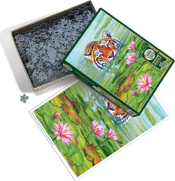 Land of the Lotus jigsaw puzzle by Cobble Hill, showcasing a beautiful scene with a tiger peeking out from a serene pond surrounded by lily pads and flowers. The box is partially open, revealing the puzzle pieces inside, which are gray and intricately shaped. The artistic image includes vibrant greens and pinks, offering a picturesque view of nature.