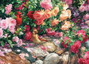 A vibrant jigsaw puzzle titled 'The Garden Wall' by Cobble Hill, featuring a lush arrangement of roses in various colors, with two birds—a red cardinal and a brown bird—nestled within the flowers. The background displays a stone pathway, enhancing the serene garden atmosphere.