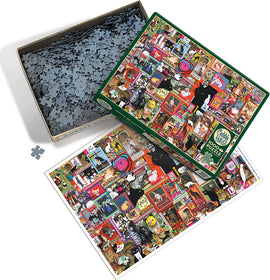 Catsville jigsaw puzzle by Cobble Hill, featuring an intricate collage of colorful cat-themed artwork and vintage illustrations on the puzzle box. The box is open, revealing numerous interlocking puzzle pieces inside, with a preview image of the completed puzzle beside it.