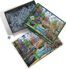 Cobble Hill 1000-piece jigsaw puzzle featuring a vibrant Amsterdam canal scene. The box is open, showcasing numerous puzzle pieces and a colorful image of bicycles by the water, charming houses, and lush greenery.