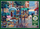 A beautifully illustrated jigsaw puzzle titled 'Rainy Day Stroll' by Cobble Hill features a charming street scene with a vintage metro station, flower stalls, and quaint cafes. The artwork captures the essence of a rainy day in an urban setting, complete with a figure holding an umbrella and the Eiffel Tower in the background, making it an ideal piece for puzzle enthusiasts.