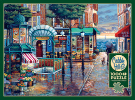 A beautifully illustrated jigsaw puzzle titled 'Rainy Day Stroll' by Cobble Hill features a charming street scene with a vintage metro station, flower stalls, and quaint cafes. The artwork captures the essence of a rainy day in an urban setting, complete with a figure holding an umbrella and the Eiffel Tower in the background, making it an ideal piece for puzzle enthusiasts.