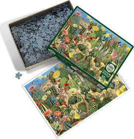 A vibrant jigsaw puzzle titled 'Cactus Garden' by Cobble Hill, displayed in an open box. The puzzle features intricate illustrations of various cacti, flowers, and plants in a colorful landscape. The image includes a close-up view of some puzzle pieces alongside the box.